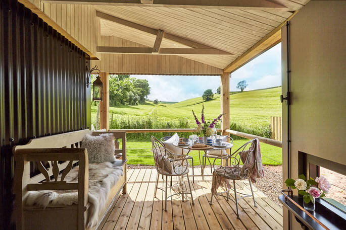 Sit on Brownscombe Cabin's covered outside deck to have breakfast with countryside views across the neighbouring barley fields