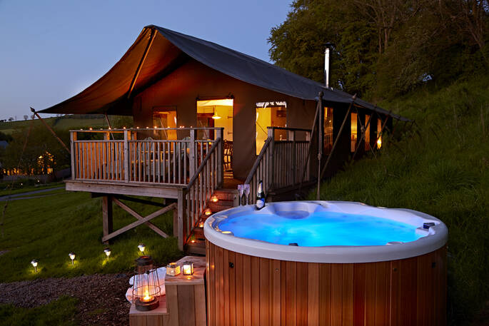 The Tamar safari tent at dusk with a glowing hot tub
