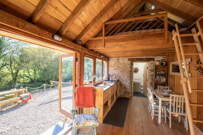 Inside the rustic and cosy Linhay barn at Butterhills, with kitchen and kingsize bed on the mezzanine level accessed via ladder