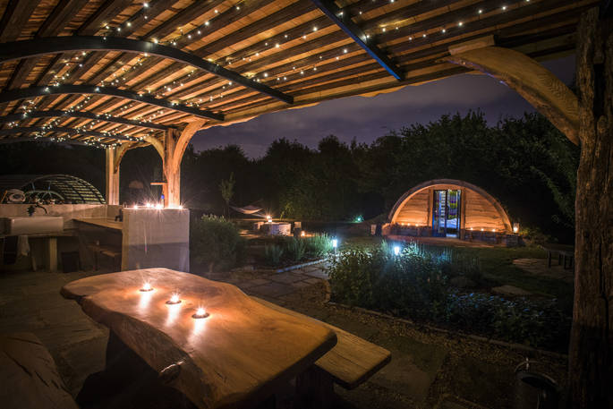 The covered outdoor kitchen and dining area at The Secret Garden with candles and fairy lights at night