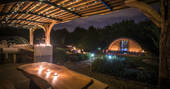 The covered outdoor kitchen and dining area at The Secret Garden with candles and fairy lights at night