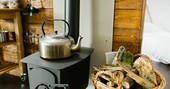 Kettle and log burner inside The Cribbau tent at Penhein Glamping in Monmouthshire